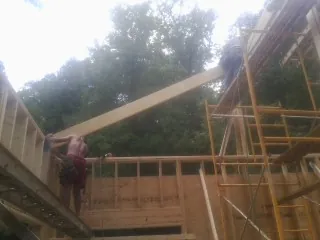 Carpenter raising a rafter beam on a new second story frame in Catawissa